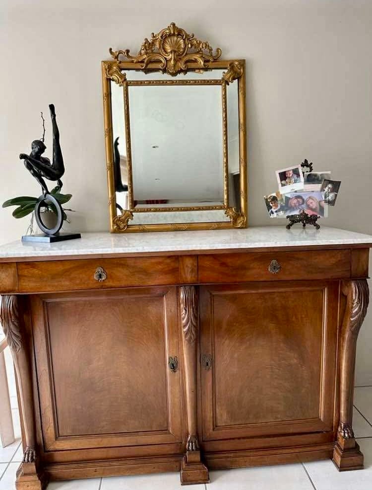 Miroir ancien à parcloses posé sur un buffet en bois et marbre